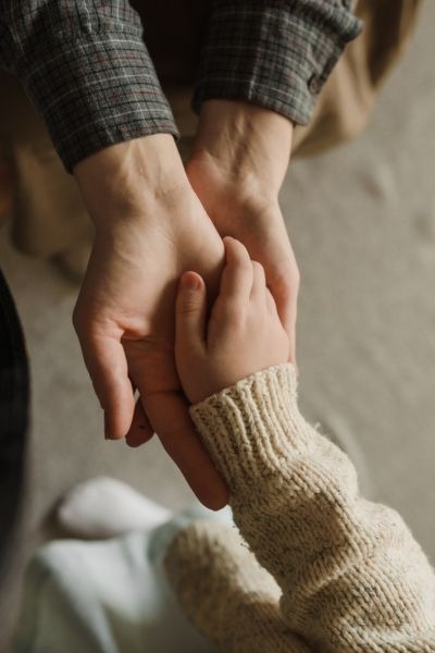 guía para entender las necesidades emocionales de los niños Mano de un padre sosteniendo la mano de su hijo, simbolizando el Círculo de Seguridad Parental. Refugio seguro y conexión emocional en la crianza.